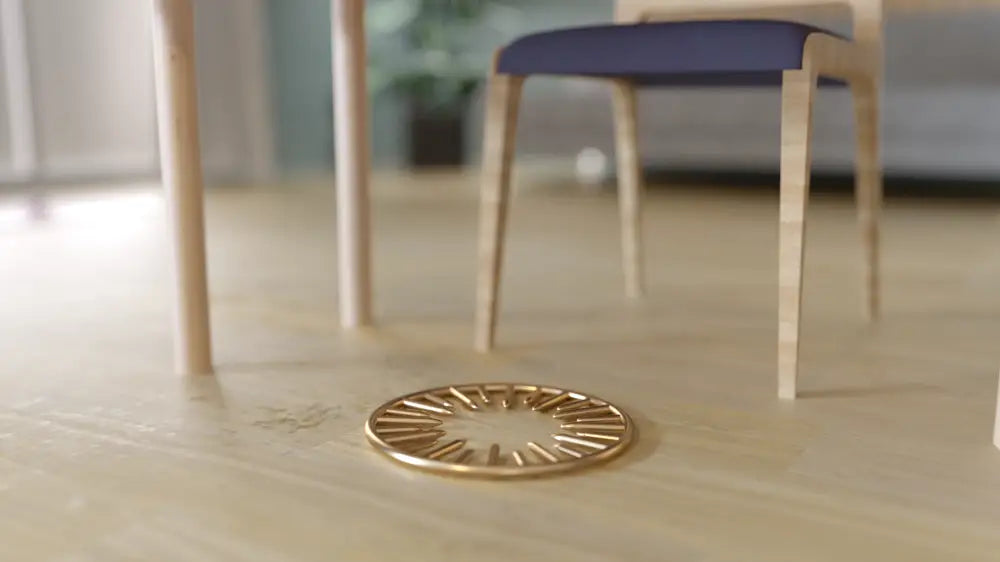 Gold Neutralizing ring coaster with spoke design on wood floor