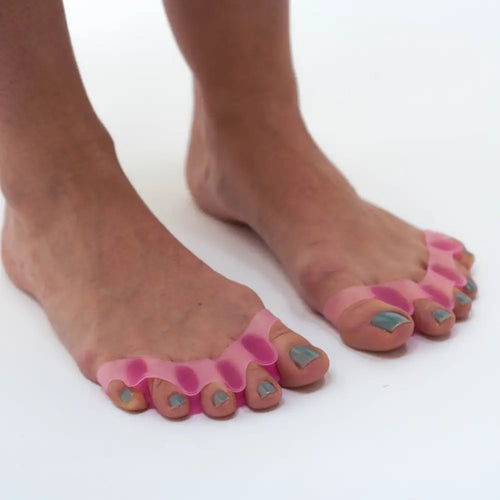 Pink silicone toe separator from Toe Trainers on feet
