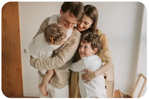 A warm-toned family portrait featuring a man, woman, and two children in soft beige and white clothing.