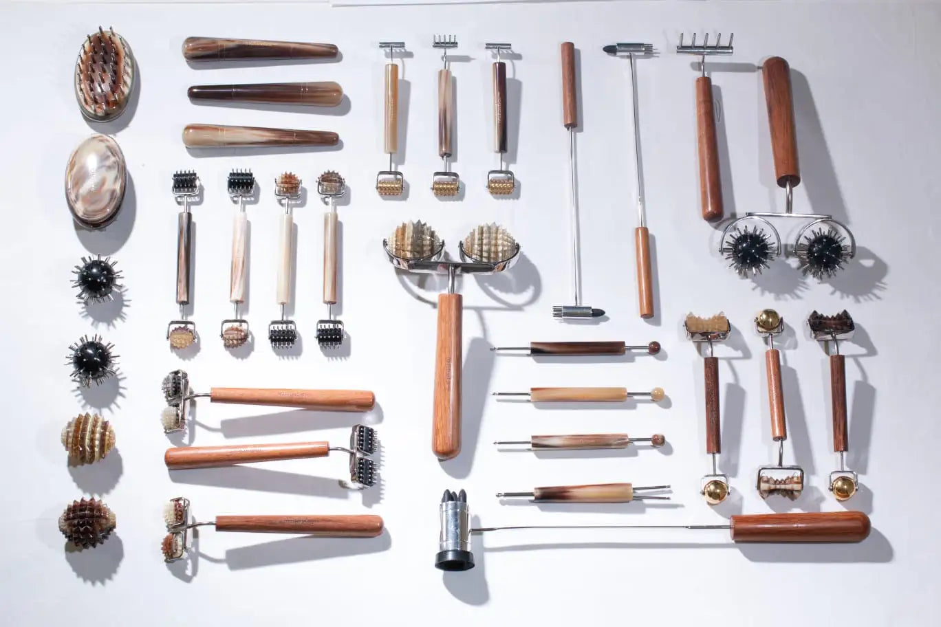 Wooden massage tools set with metal heads and handles, various designs including spherical, cylindrical, and textured surfaces.